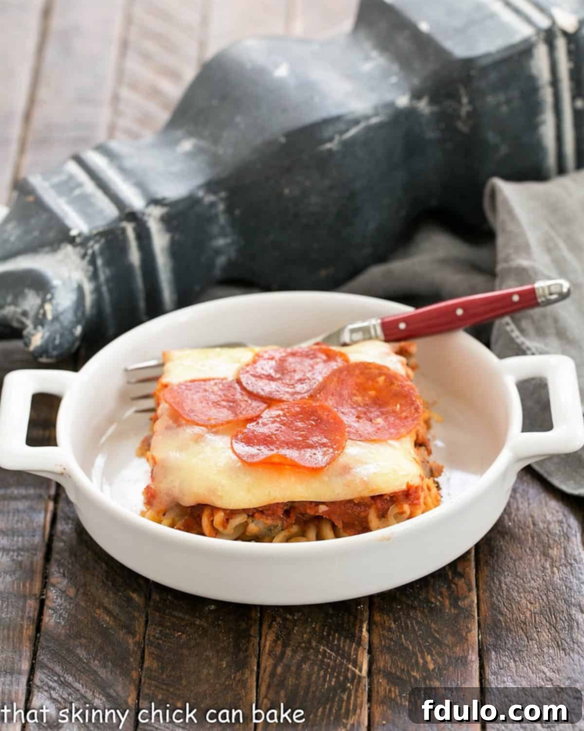Side view of pizza bake in a small white casserole dish.