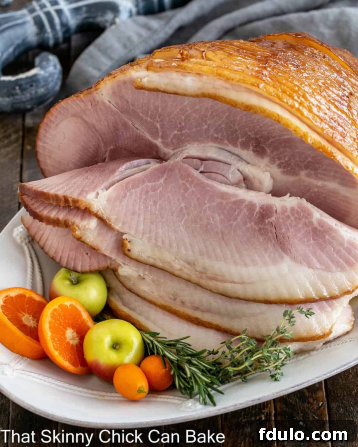 Honey Mustard Glazed ham on a white platter with fruit garnishes.