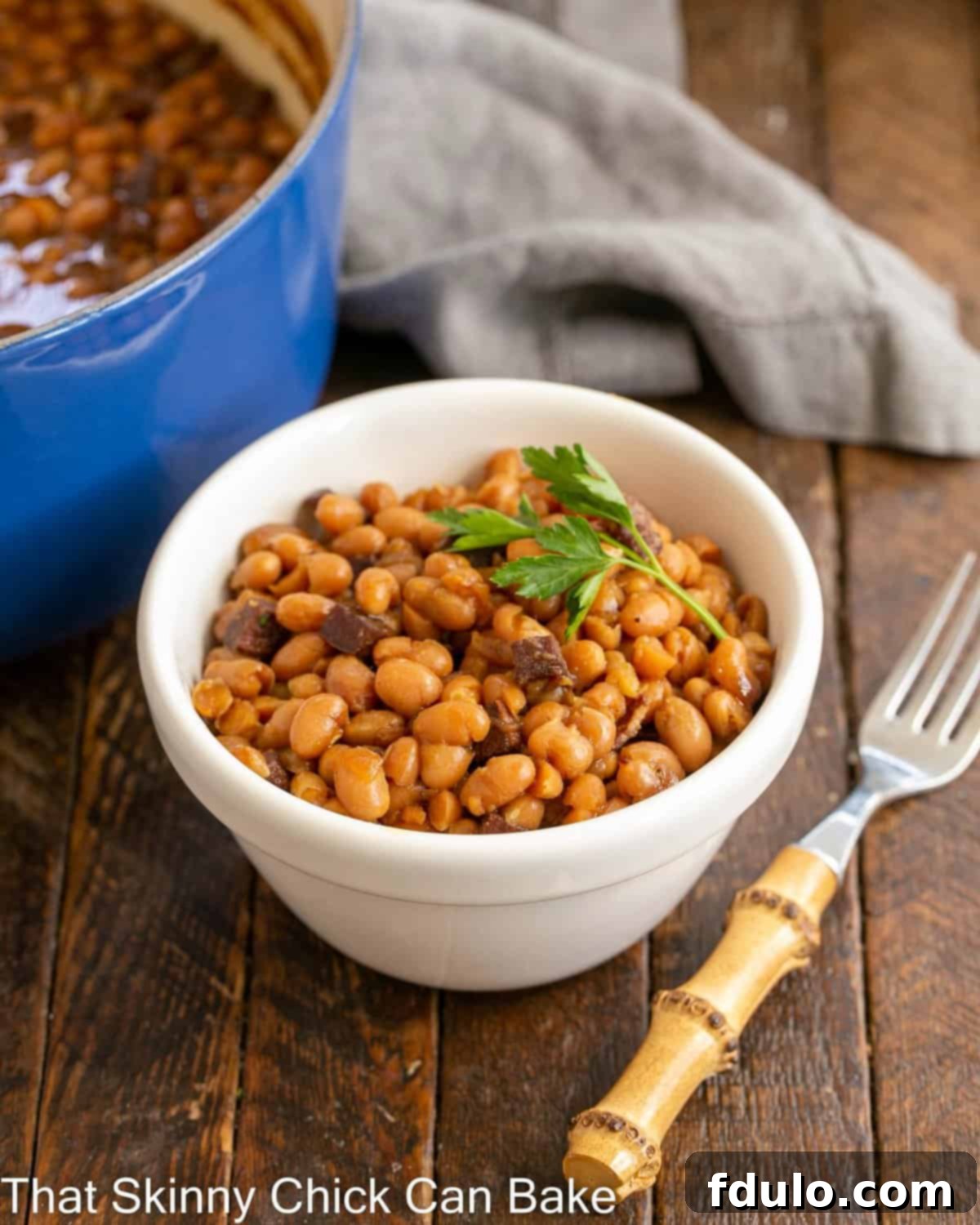 Grandma's Classic Baked Beans 2 Bowl of boston baked beans in a white bowl with a bamboo fork.