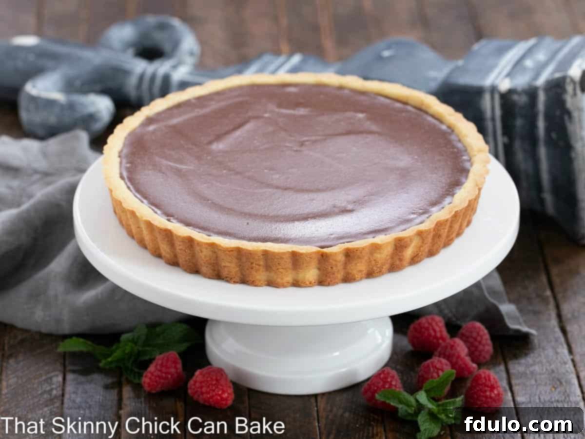 Whole milk chocolate tart on a white cake stand.