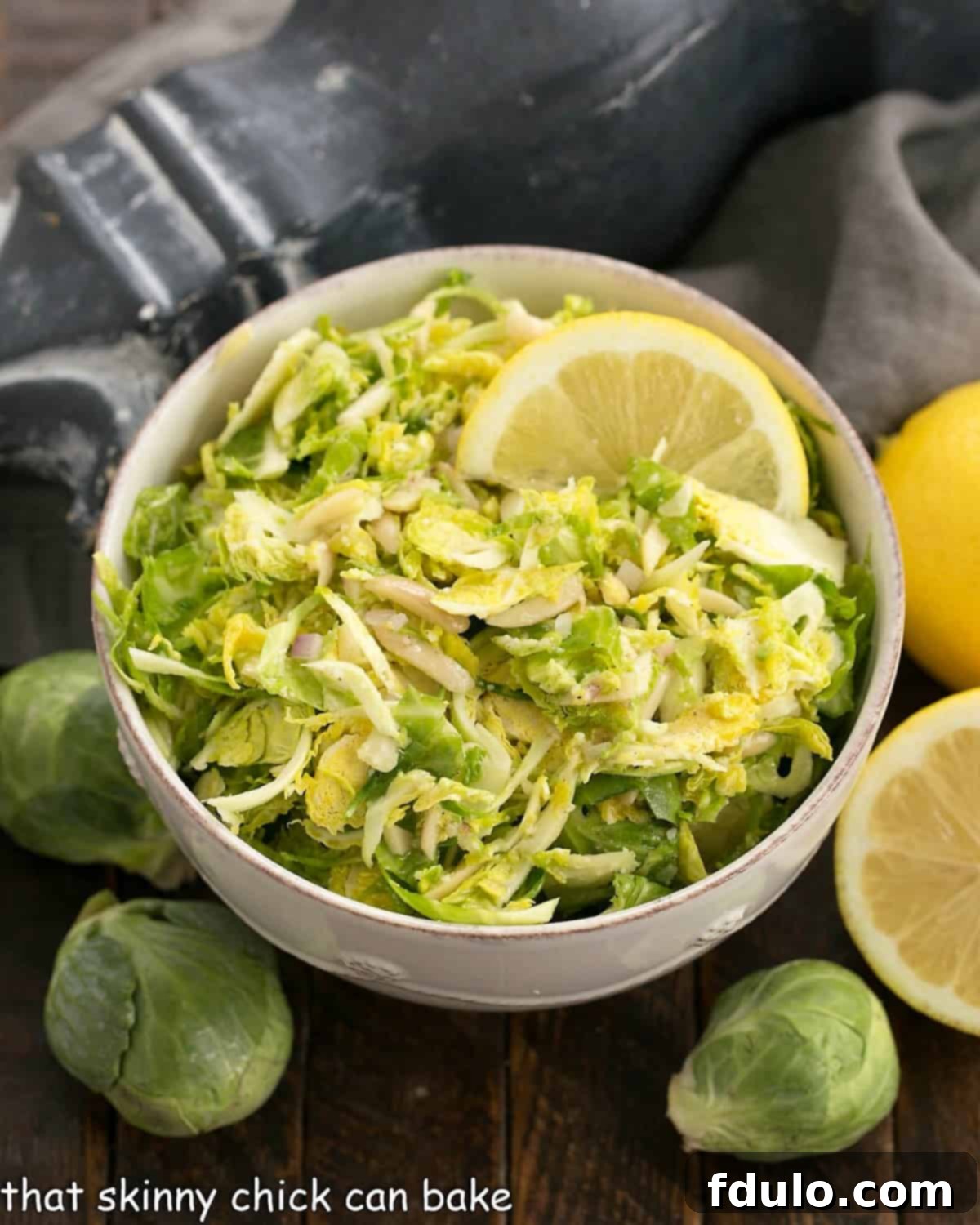 A vibrant Shaved Brussels Sprouts Salad served in an elegant white ceramic serving bowl, showcasing its fresh green color and enticing texture.