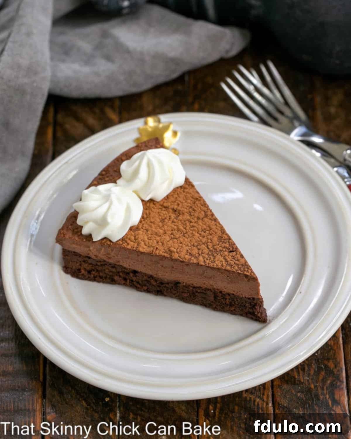 A meticulously cut slice of Whipped Ganache Chocolate Cake, showcasing the distinct layers of dense cake and airy chocolate ganache, garnished with a delicate swirl of whipped cream and a sprinkle of cocoa powder.