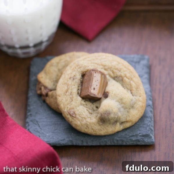 Two golden-brown Milky Way Cookies resting on a grey stone coaster atop a rustic wooden table.