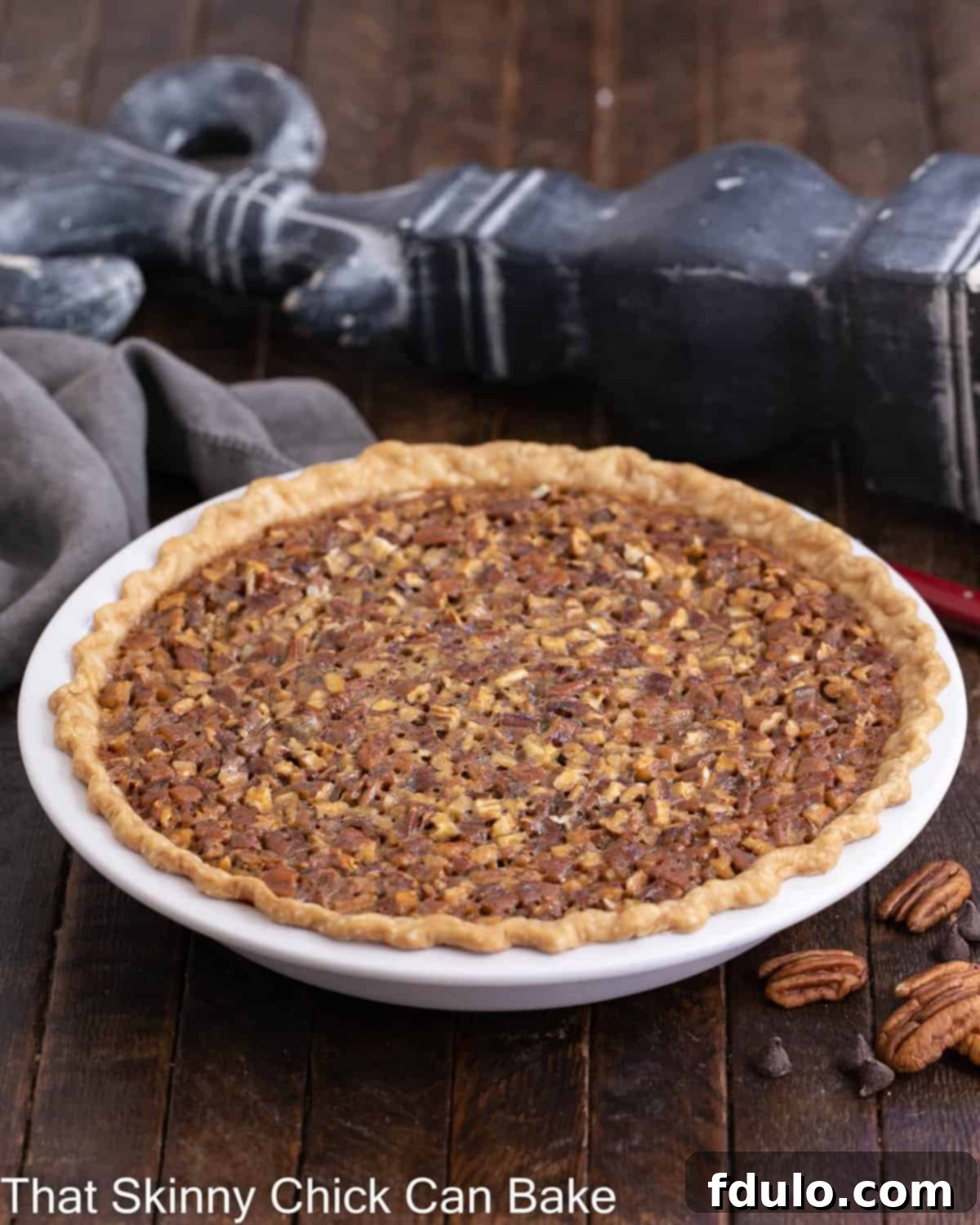 Side view of a whole, uncut Chocolate Pecan Pie, showcasing its golden crust and inviting top.