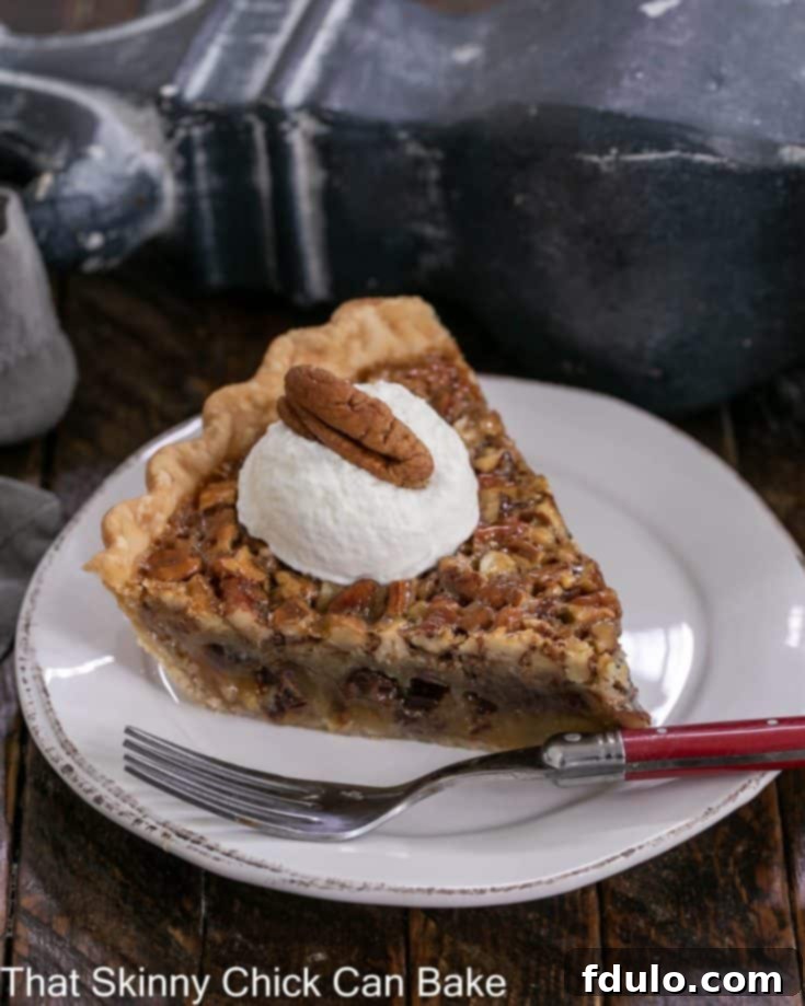 Slice of Derby pie on a dessert plate topped with whipped cream and a pecan, looking absolutely divine.