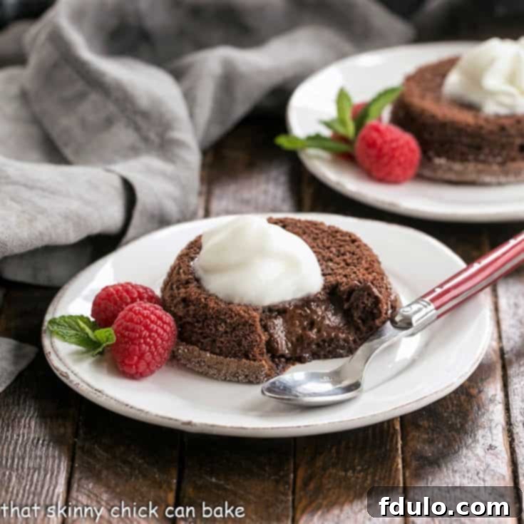 Kahlua-Kissed Lava Delight 2 Two lava cakes on white dessert plates with berries, mint and whipped cream to garnish