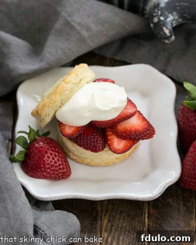 Classic Strawberry Shortcakes on a square white plate with a half strawberry garnish, emphasizing their homemade appeal.