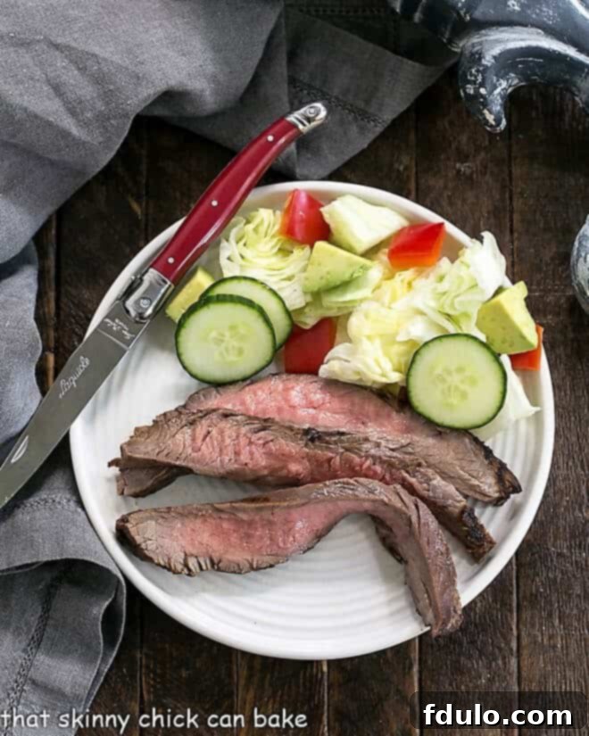 Flank steak marinated in a Soy, Orange Juice, Red Wine Marinade sliced on a round white plate, ready to serve.