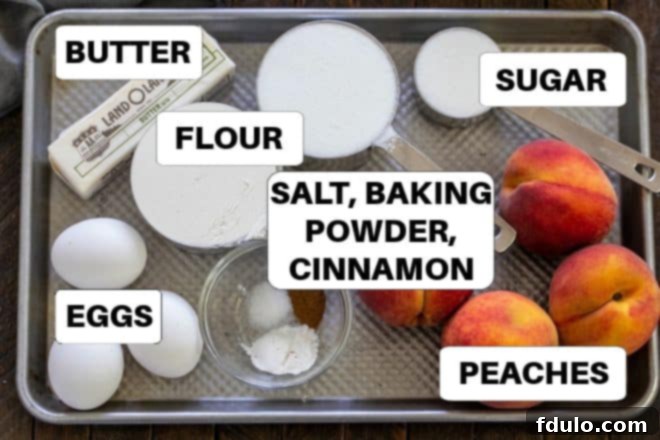 All the fresh ingredients for peach upside down cake, including ripe peaches, butter, flour, sugar, and eggs, neatly arranged on a baking sheet.