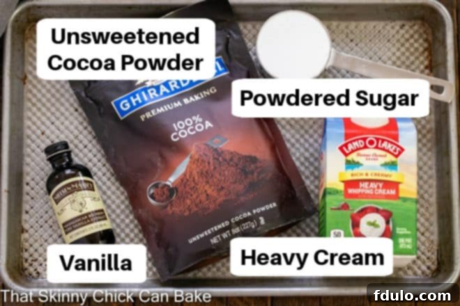 Essential ingredients for a quick chocolate mousse, neatly arranged on a sheet pan with descriptive labels: good quality unsweetened cocoa powder, heavy whipping cream, powdered sugar, and real vanilla extract.