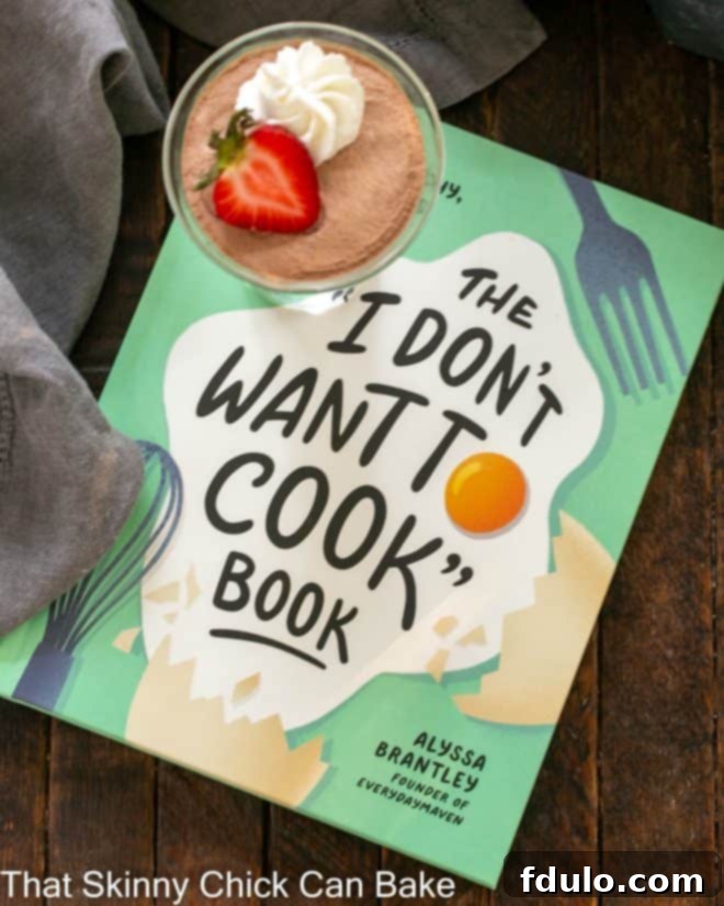 Two generous servings of 5-Minute Whipped Chocolate Mousse in elegant glass dishes, adorned with a delicate swirl of whipped cream, fresh raspberries, and a mint leaf, ready to be enjoyed.