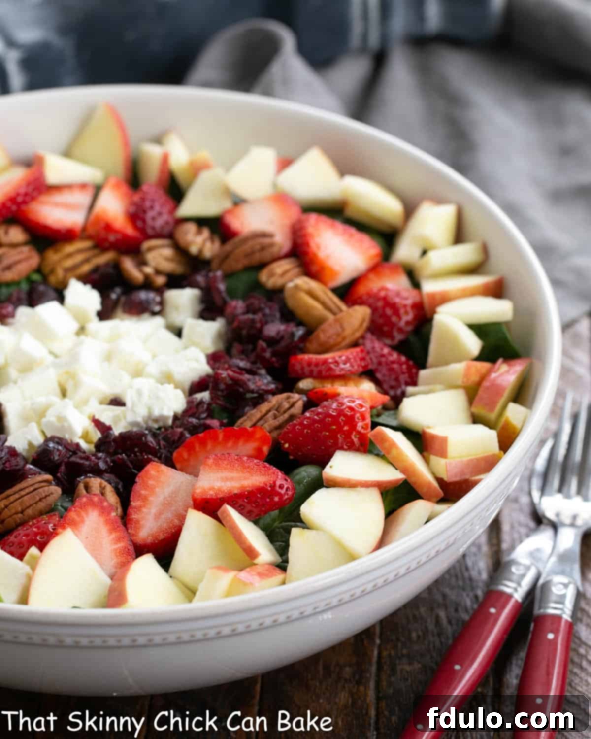 Partial view of Spinach Salad with Strawberries and Feta in a white ceramic salad bowl.