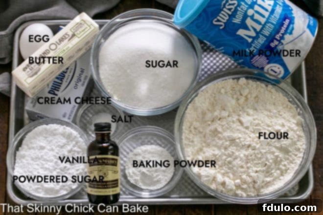 A sheet pan showcasing an array of Gooey Butter Cookie ingredients, neatly labeled, including butter sticks, cream cheese, sugar, flour, and baking powder, ready for preparation.