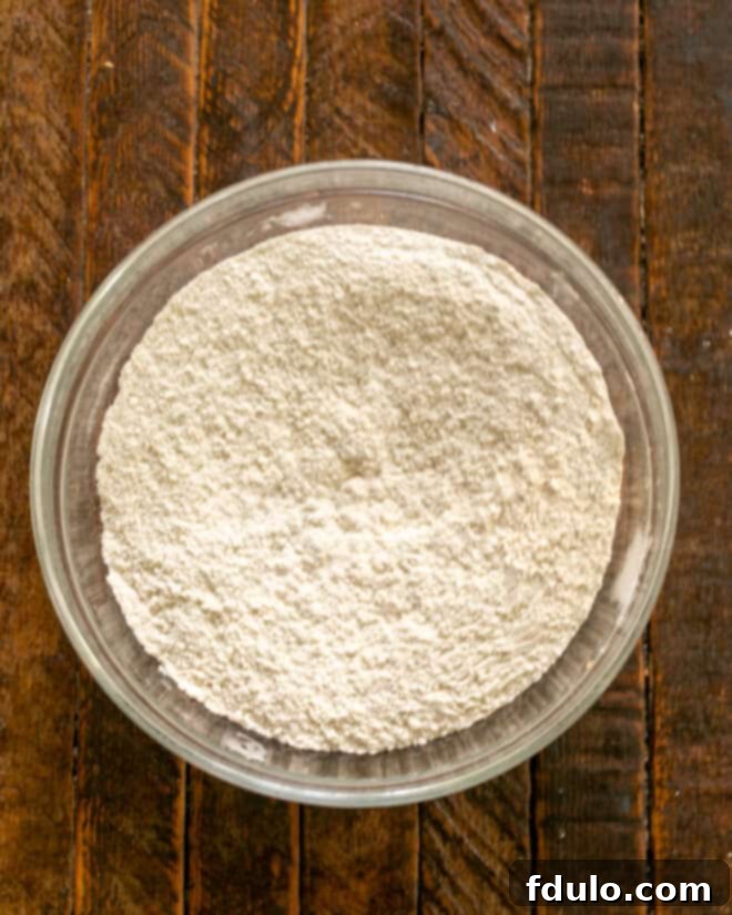 Dry ingredients in a mixing bowl, including flour, baking soda, and salt, ready to be whisked together.