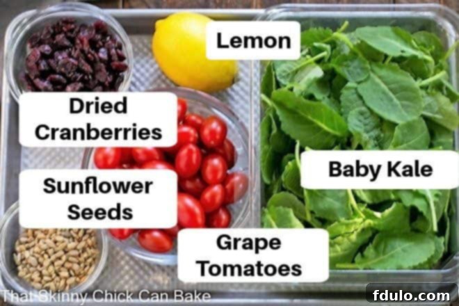 An overhead shot showcasing labeled kale salad ingredients neatly arranged on a sheet pan, ready for preparation.