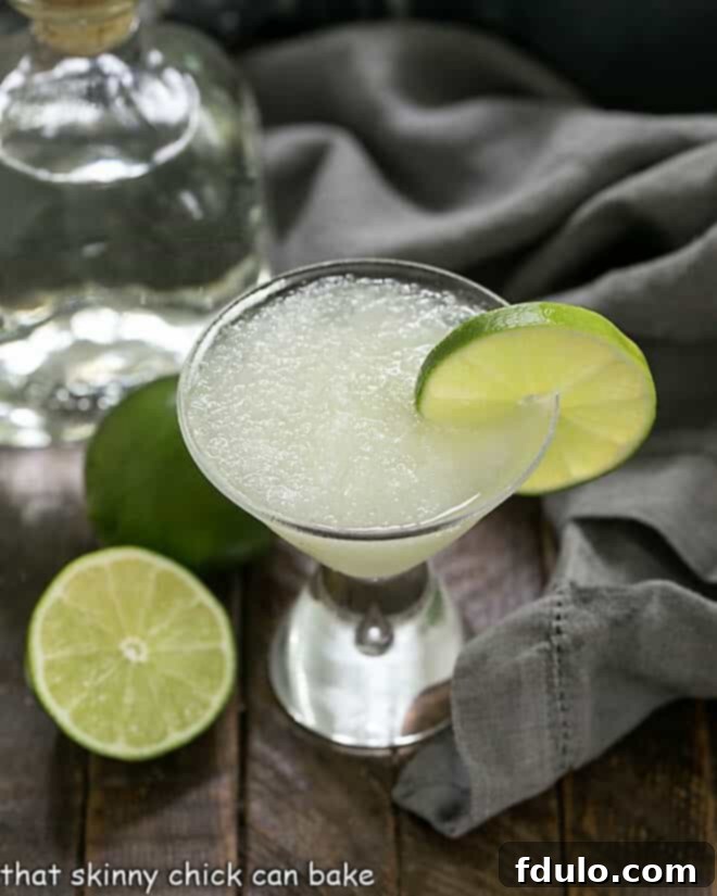 Easy 3-Ingredient Beer Margaritas with a lime garnish and tequila and limes in the background.