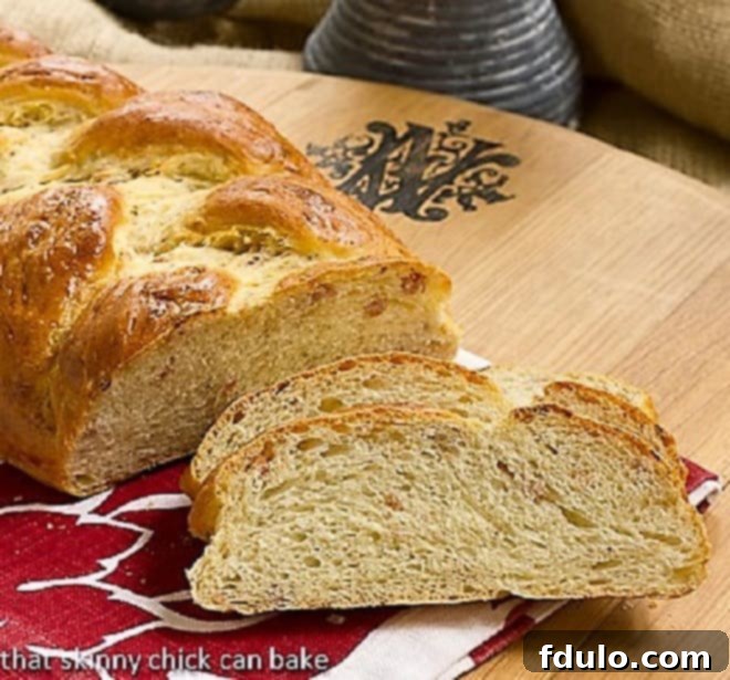 A freshly baked, golden-brown Parmesan Prosciutto Bread loaf on a rustic wooden board, partially covered by a red and white checkered napkin.