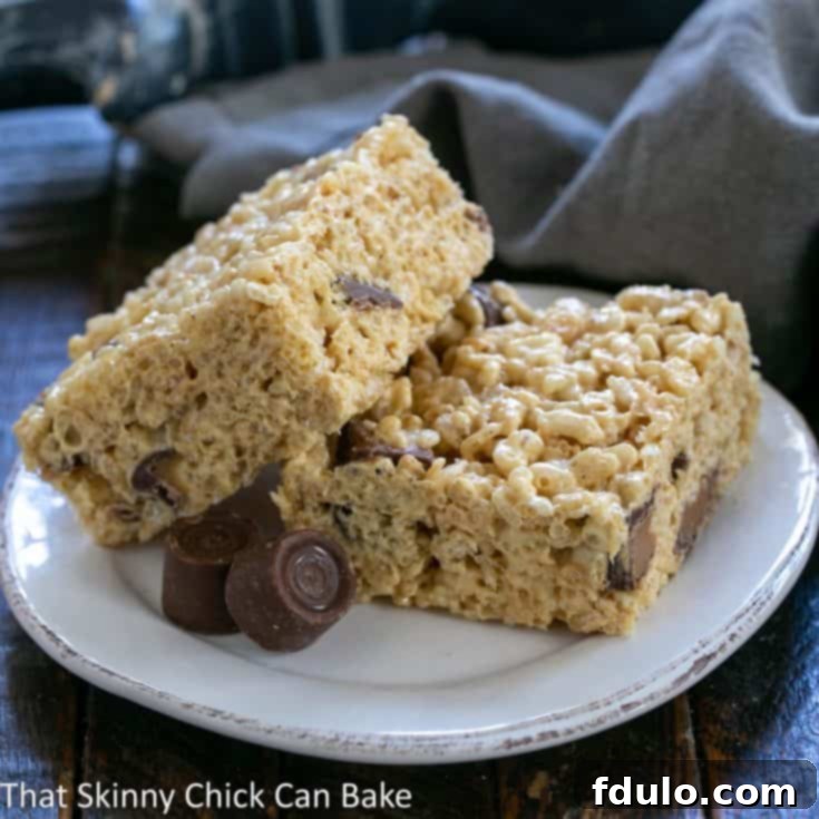 Gooey Rolo Caramel Krispie Treats 6 Two Rolo Rice Krispie Treats, one leaning on another, on a round white plate.