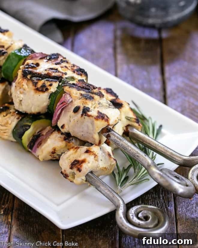Grilled Feta Chicken Kabobs beautifully arranged on a white serving tray, garnished with fresh herbs and lemon wedges.