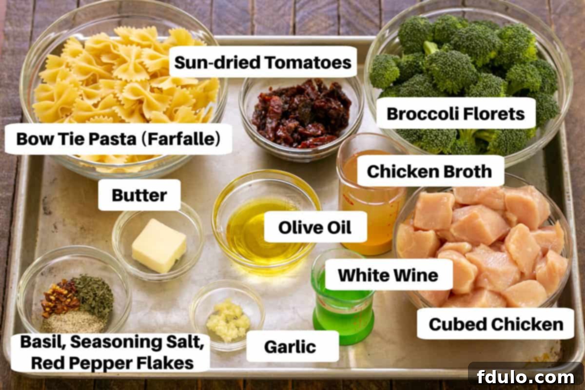A neatly arranged flat lay of all the ingredients for Chicken with Broccoli, Sun-dried Tomatoes and Bow Tie Pasta on a metal sheet pan, clearly labeled for easy identification.