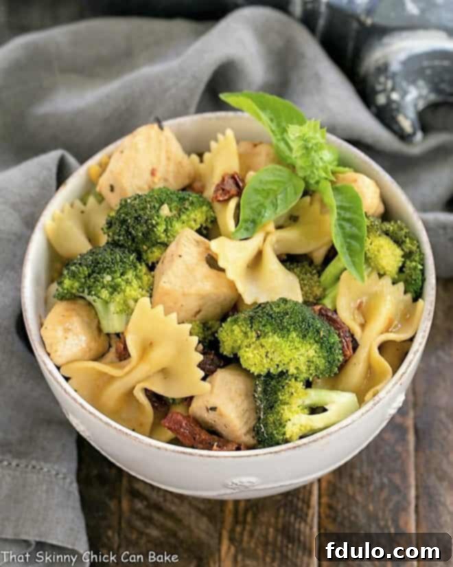 A beautifully plated serving of Chicken with Broccoli, Sun-dried Tomatoes and Bow Tie Pasta in a white ceramic bowl, ready to be enjoyed as a satisfying meal.