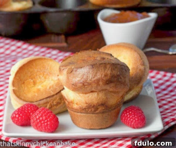 Perfect Popovers on a square white plate with fresh raspberries, hinting at a delightful pairing.