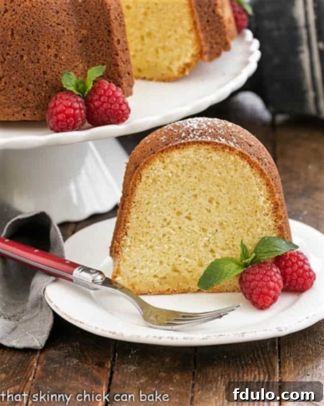 A delectable slice of White Chocolate Bundt Cake served on a white plate, garnished with fresh raspberries.