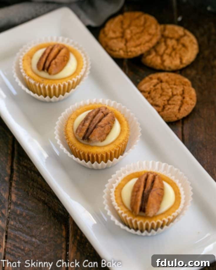 Spiced Pumpkin Cheesecake Cups 5 Mini pumpkin cheesecakes on a white ceramic tray, showcasing their perfect size and inviting appearance.