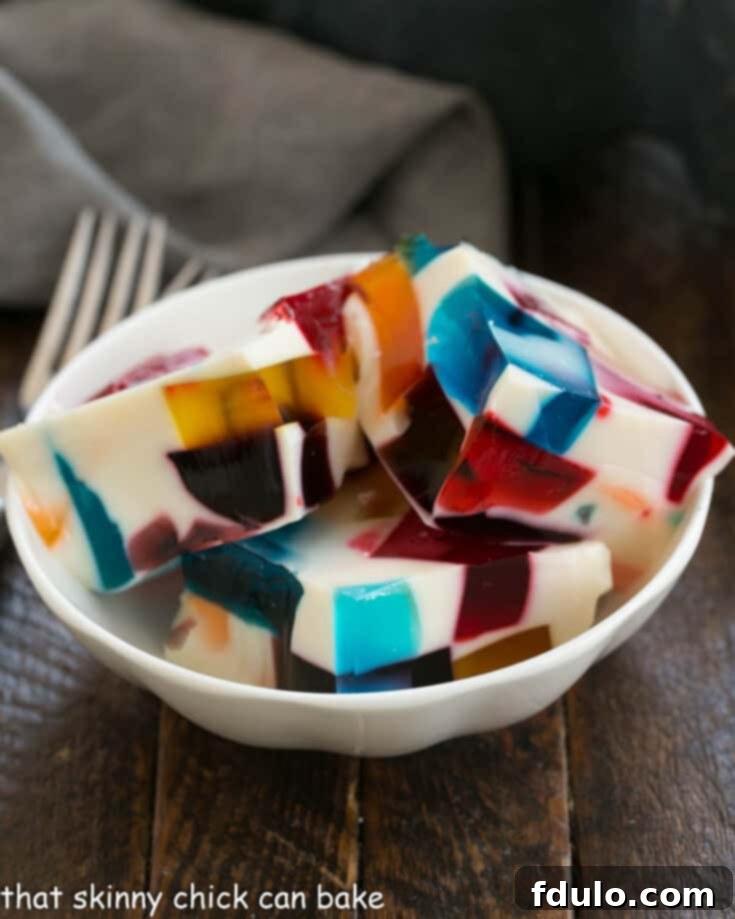 Stained Glass Dessert 5 Broken Glass Jello squares arranged in a small white serving dish, showcasing their vibrant colors.