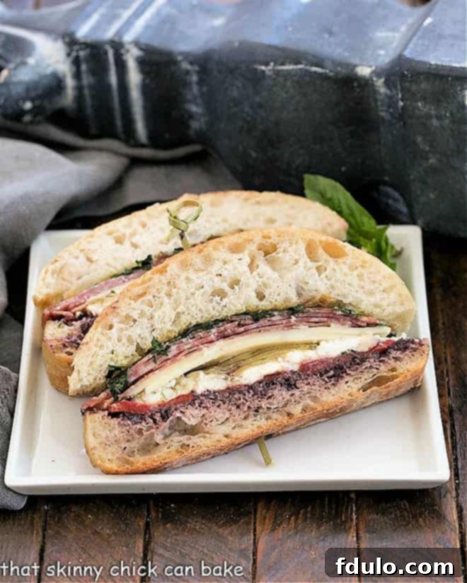 Italian Picnic Sandwich - a pressed brick sandwich filled with meat, cheese, vegetables and olive paste. Perfect for sharing with family and friends Slices of picnic sandwich on a white plate.