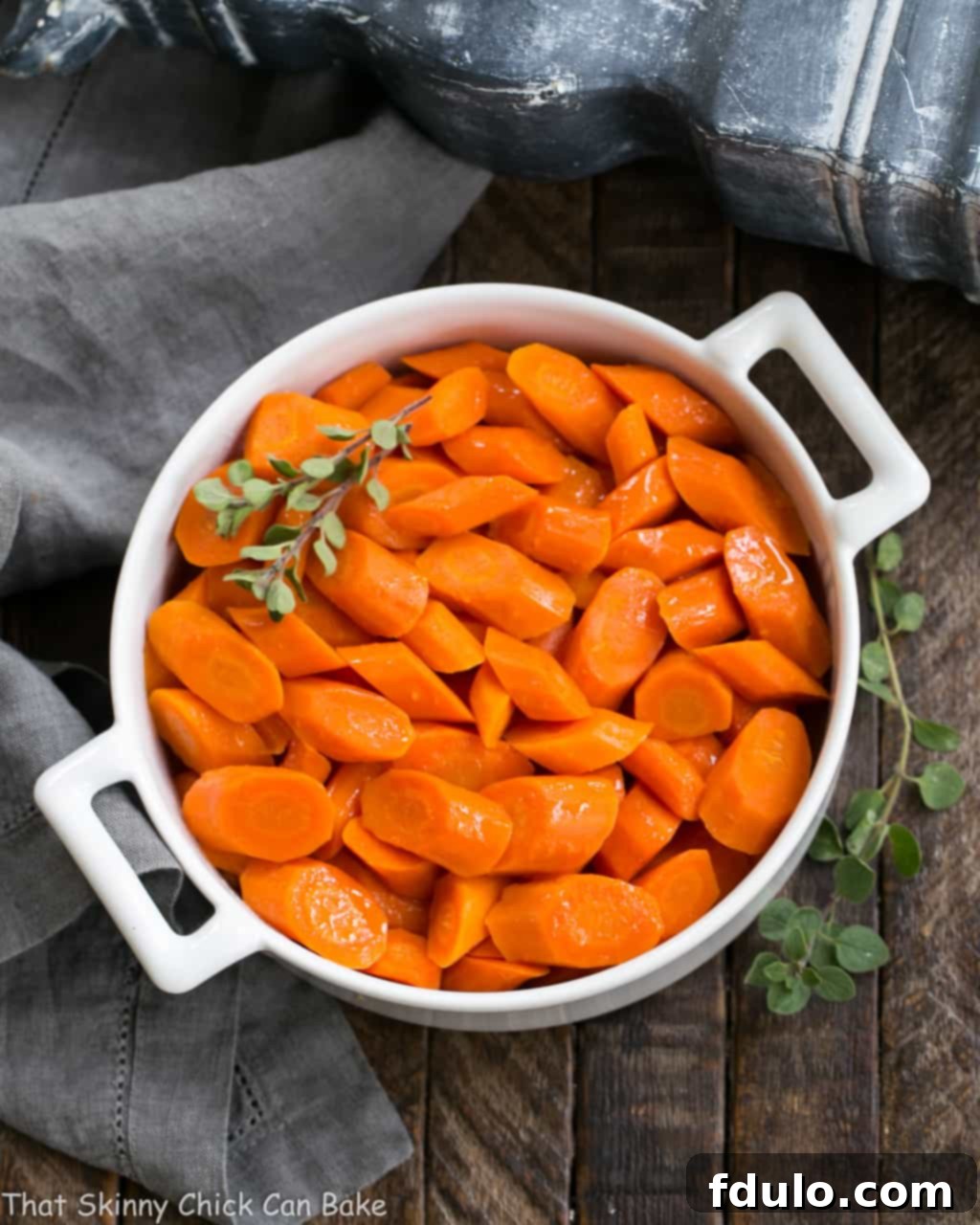 Bourbon Maple Glazed Carrots - An easy way to transform carrots into a restaurant worthy side dish! Serving dish of Bourbon Maple Glazed Carrots garnished with fresh herbs, ready for a holiday meal.