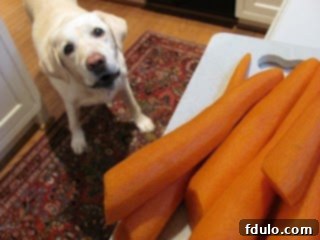 Bourbon Maple Glazed Carrots - An easy way to transform carrots into a restaurant worthy side dish! Behind-the-scenes prep of carrots, showing fresh carrots being peeled and sliced on a cutting board.