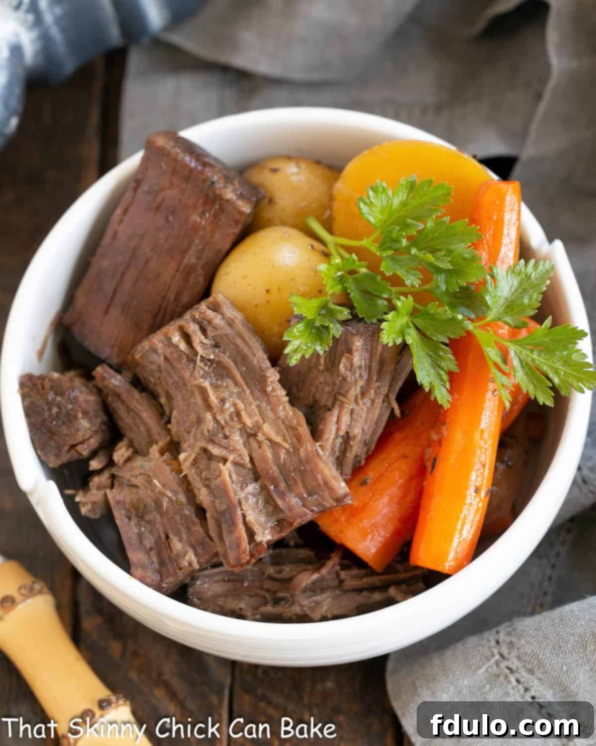 Tender Beef Chuck Roast 2 Beef Chuck Roast dished out into a white bowl with tender carrots and potatoes, ready to serve.