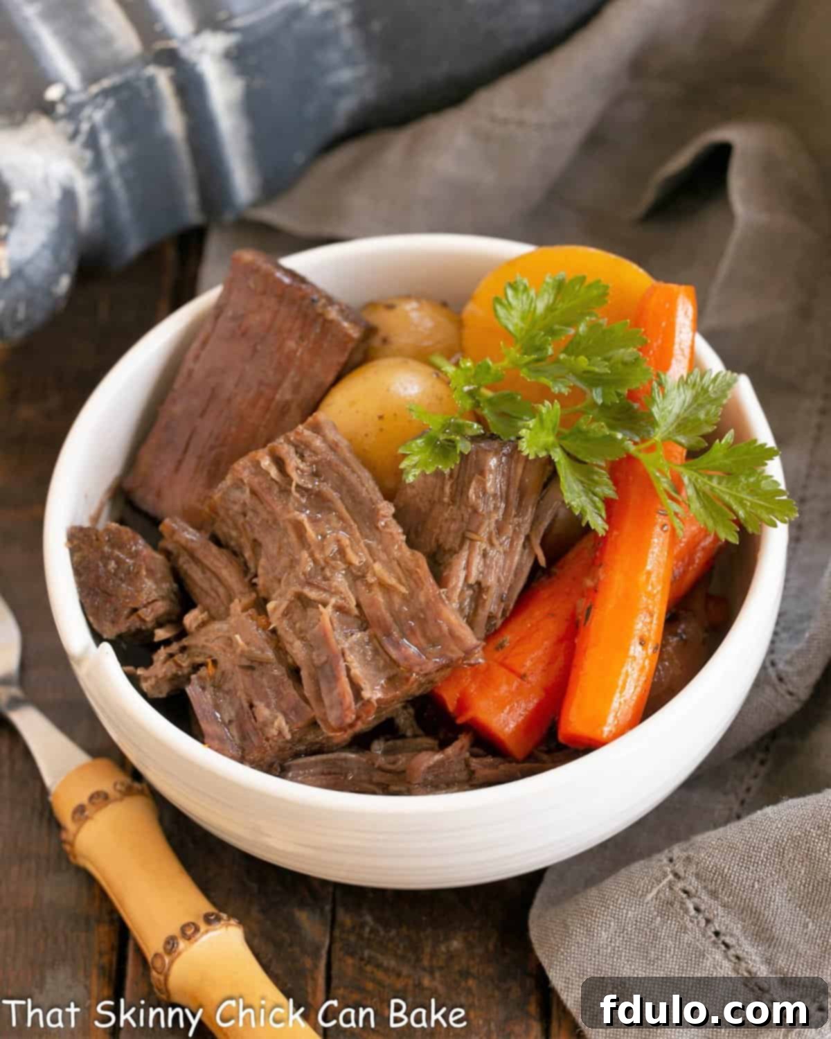 Tender Beef Chuck Roast 4 Pot roast garnished with fresh parsley in a white bowl, ready to be enjoyed.