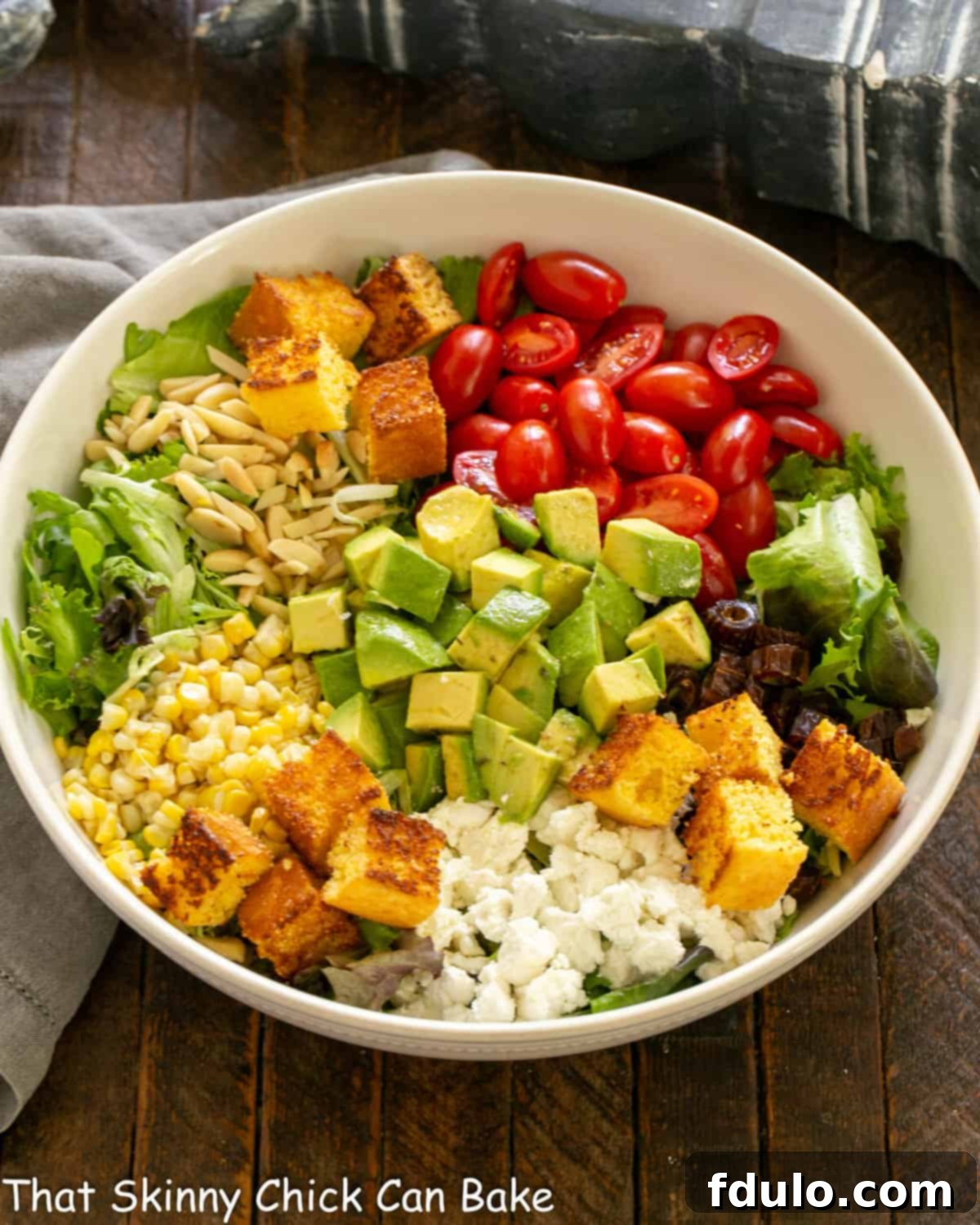 A vibrant Macho Salad displayed in a stylish white serving bowl, showcasing fresh ingredients like corn, tomatoes, and leafy greens.