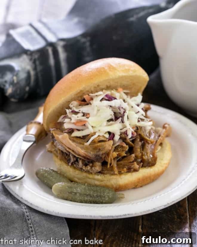 Pulled Pork Sandwiches topped with slaw on a round white plate.