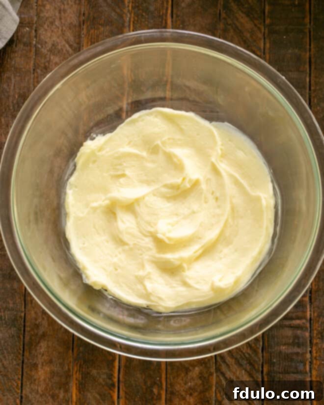 Softened butter and powdered sugar being beaten together in a mixing bowl until light and fluffy.