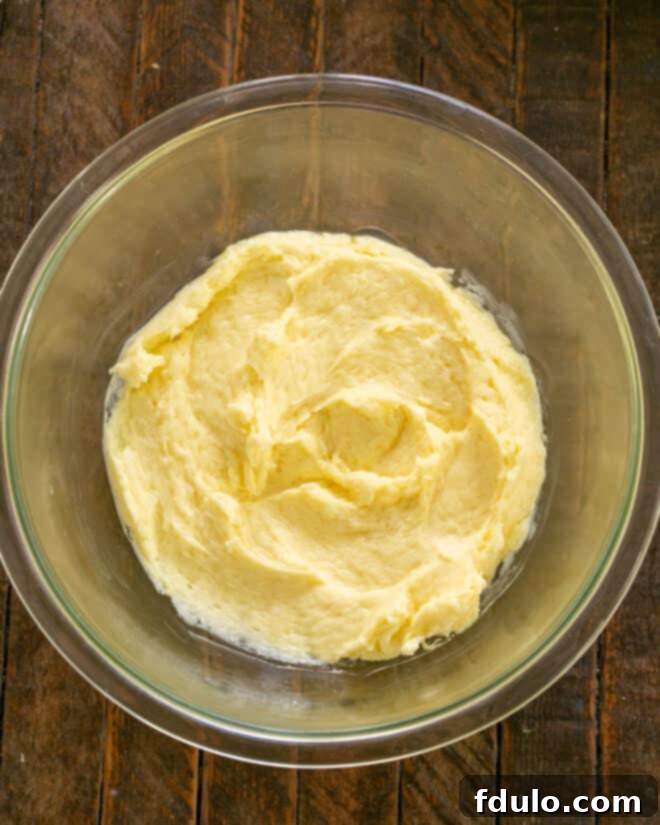 Egg added to butter and sugar in a mixing bowl, followed by vanilla and lemon extracts.