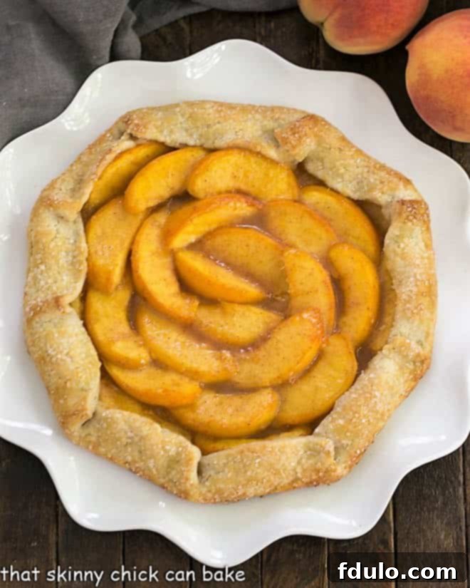Overhead view of a beautiful Rustic Peach Galette on a ruffled white serving plate, showcasing its golden crust and juicy peach filling.