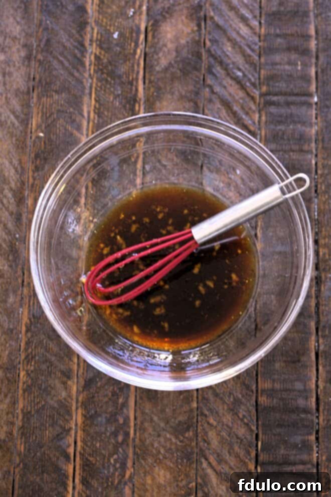 Salmon marinade in a bowl with a whisk, showcasing the process of combining ingredients.