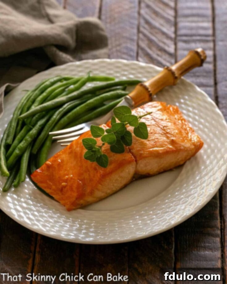 Marinated salmon for two on a white plate with a fork and green beans, a perfect healthy meal.