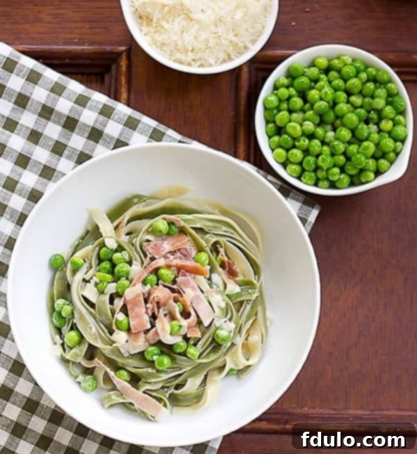 An inviting overhead view of Straw and Hay Pasta, rich with cream sauce, peas, and prosciutto, served in a pristine white bowl.