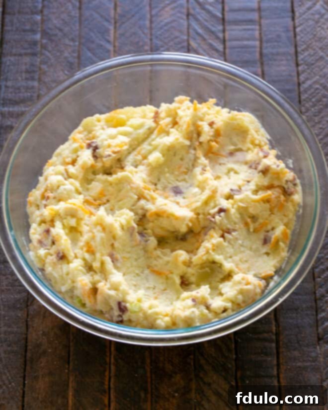 Twice Baked Potato Casserole Step 3: Mixing in a whisked egg, spreading into a casserole dish, and topping with more cheese.