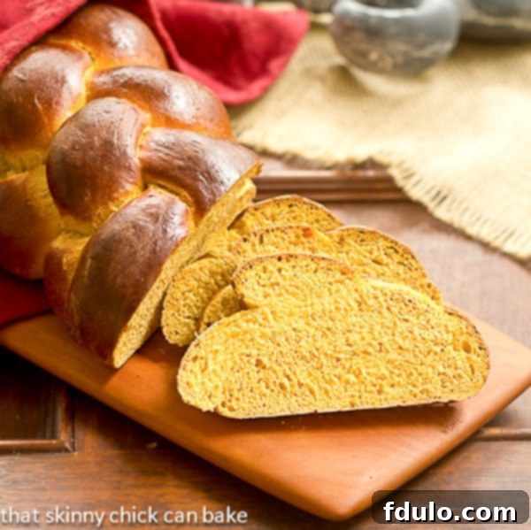 Slices of fluffy pumpkin challah arranged on a wooden cutting board, highlighting its moist interior.