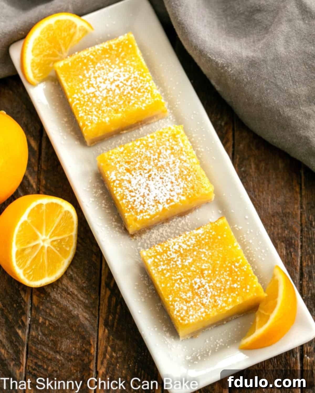 Overhead view of a tray of 3 meyer lemon bars with small lemon slices to garnish.