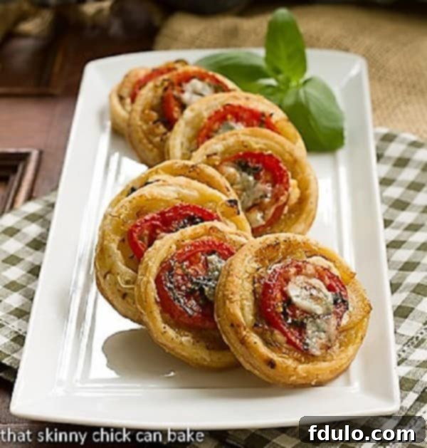 Tomato and Boursin Tartlets on a white ceramic tray, showcasing their golden crust and vibrant toppings.