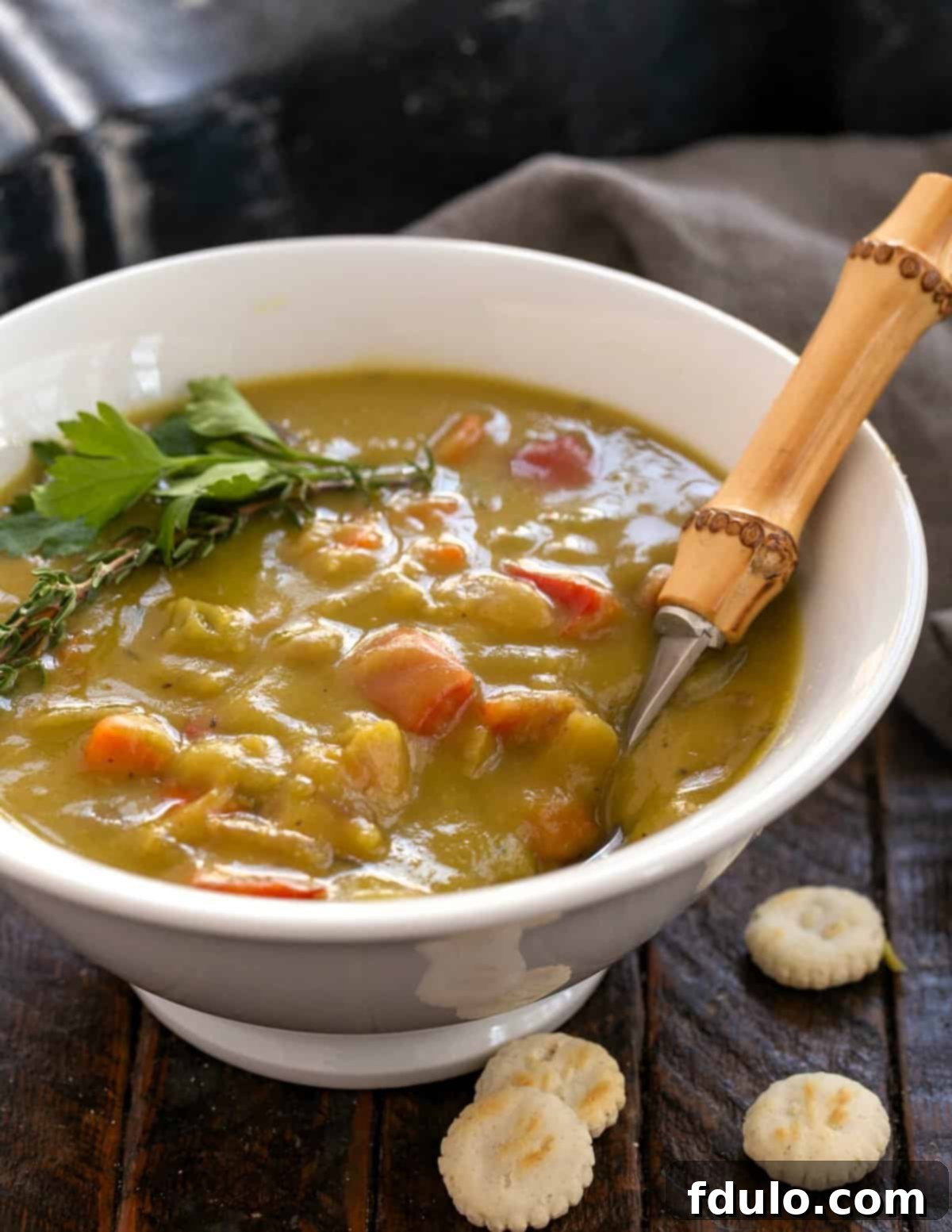 A large bowl of homemade Split Pea and Ham Soup, garnished with fresh herbs, ready to be served on a rustic wooden table.