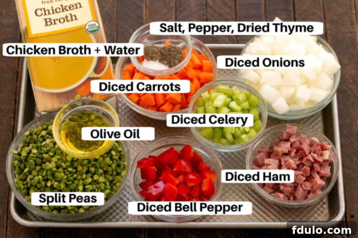 Various ingredients for Split Pea Soup, including green split peas, diced ham, carrots, celery, onion, and herbs, arranged on a metal sheet pan.