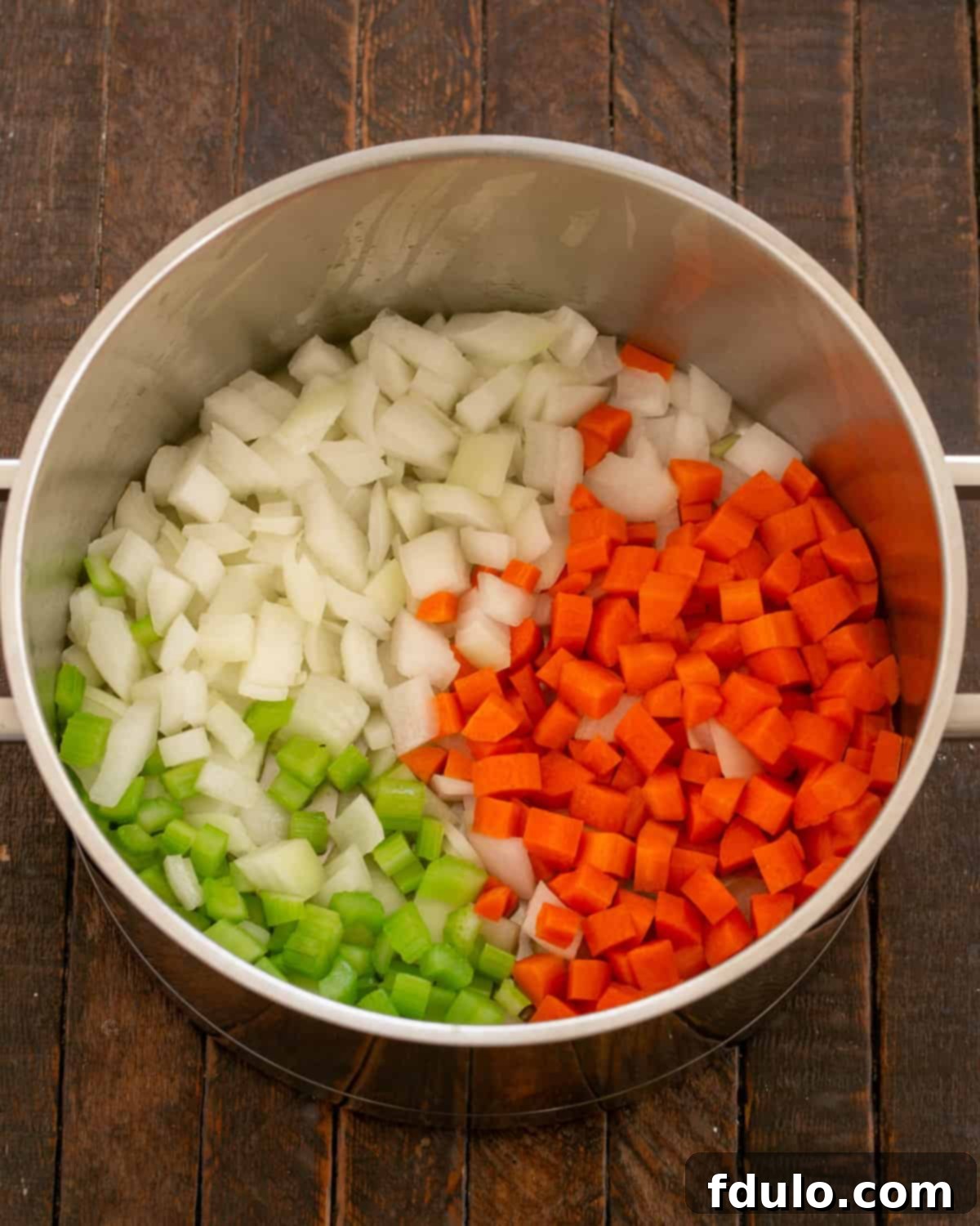 Sautéing diced onions, carrots, and celery in olive oil in a skillet.