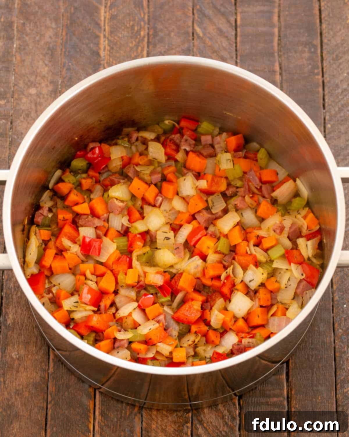 Close-up of tender, sautéed vegetables and ham in a skillet.